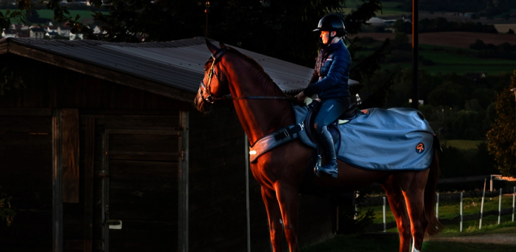 Ein Pferd und Reiter mit der New York LED Ausreitdecke in der Dunkelheit