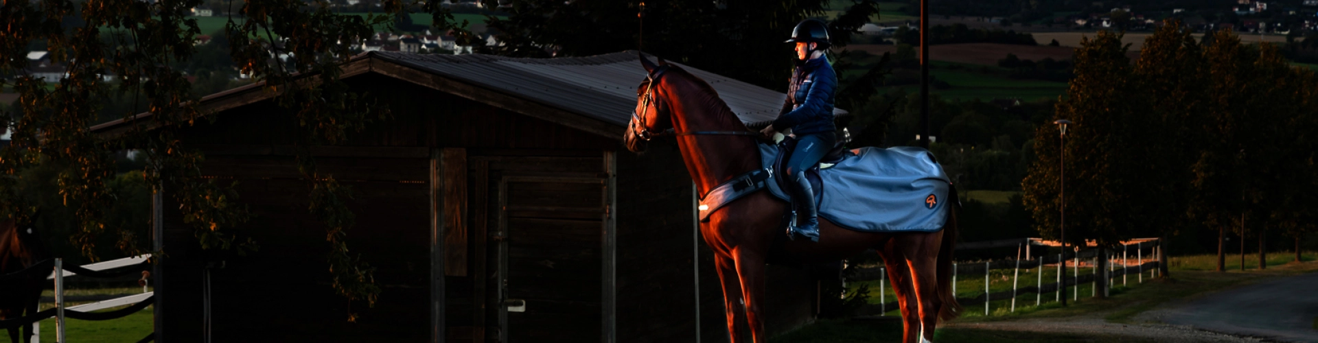 Ein Pferd und Reiter mit der New York LED Ausreitdecke in der Dunkelheit