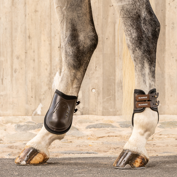 brown high leather fetlock boots with protection layer and elastic closure straps by sunride on a horse leg